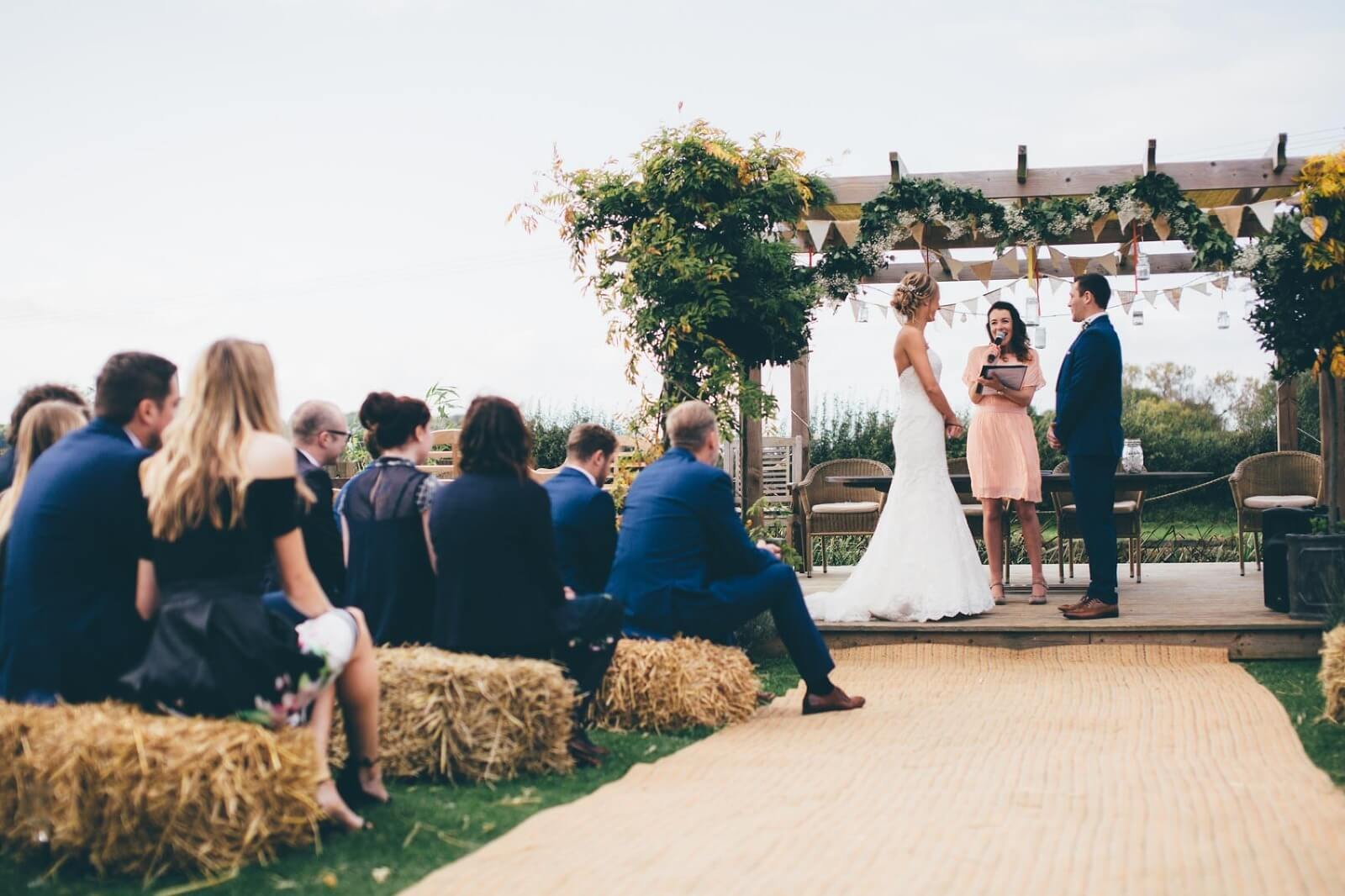 Bride and groom under wedding gardland at Bridge House Barn Leicestershire